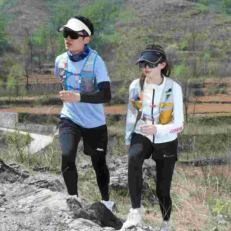 Two people trail running outdoors in sportswear and hydration packs on a rocky path