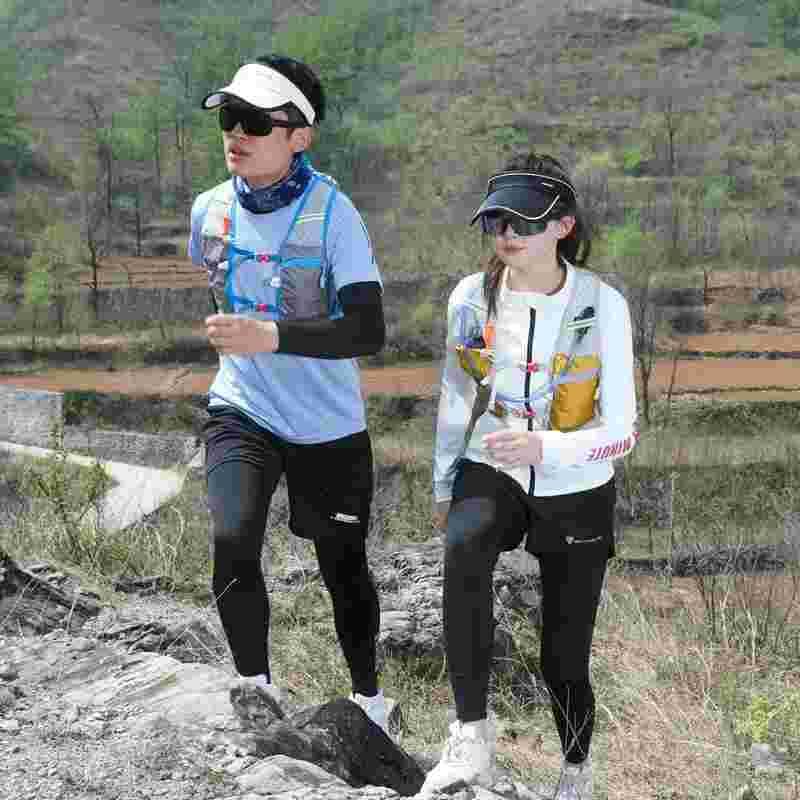 Man and woman trail running in outdoor gear, hydration vests, sunglasses, and visors on rocky terrain