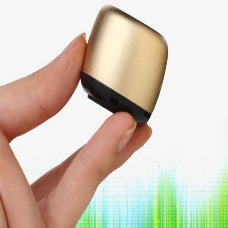Gold and black electronic device held between fingers with a colorful blurred background