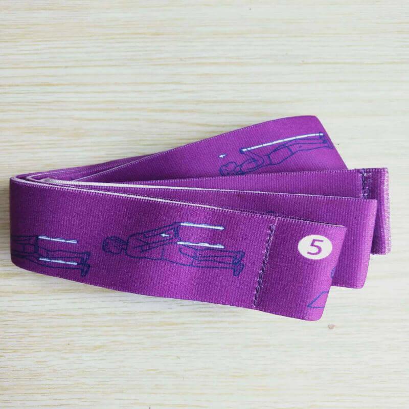 Purple fabric resistance band with exercise illustrations and level 5 marking on wooden surface