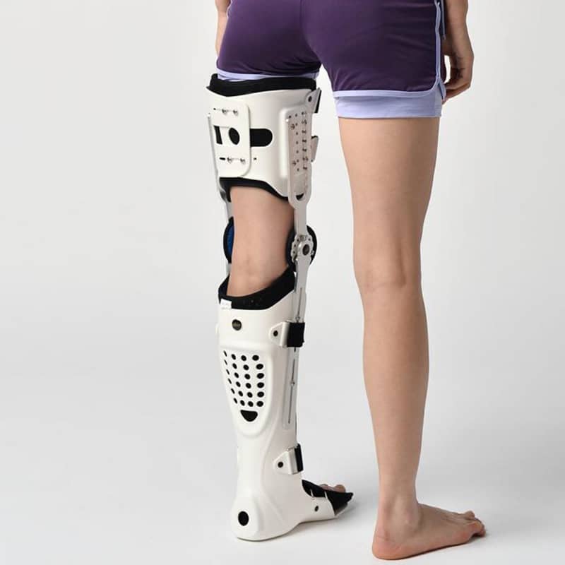White orthopedic leg brace on a person's leg against a white background