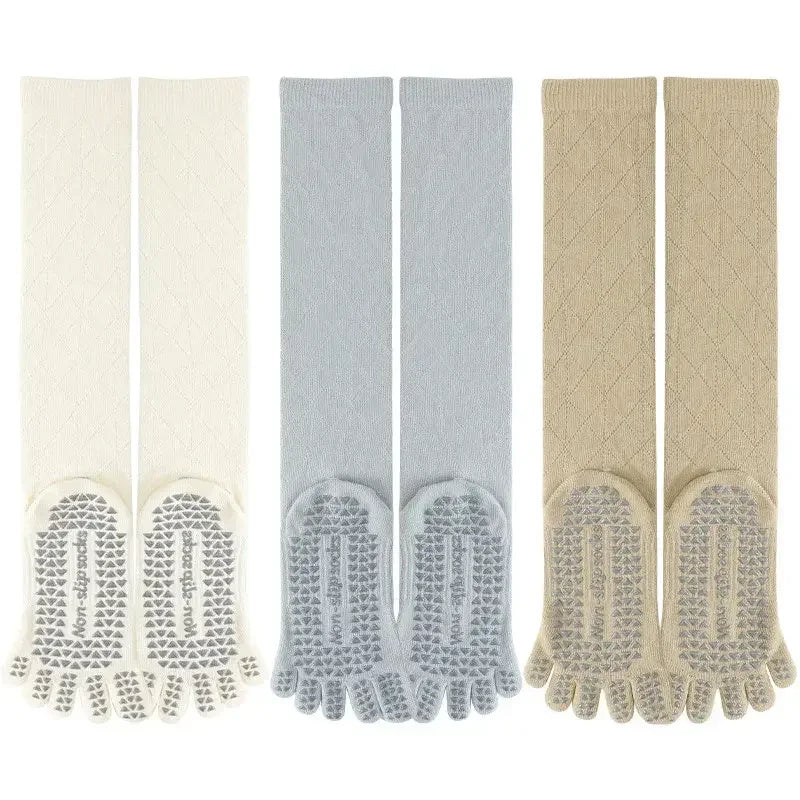 Three pairs of knee-high toe socks with grip soles, in cream, gray, and beige, for yoga or fitness.