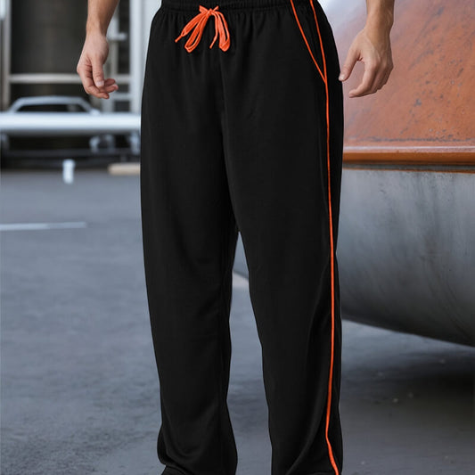 Black pants with orange drawstring and side stripe worn by a person on an urban street.