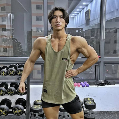 Muscular man in a green tank top posing in a gym.