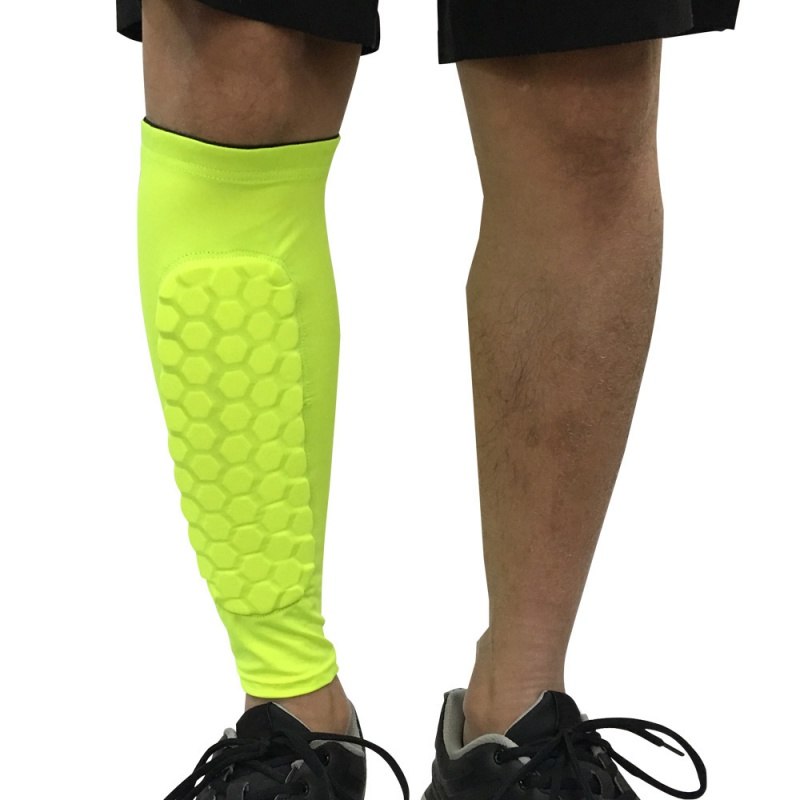 Bright yellow shin guard on a person's leg against a white background
