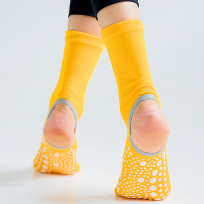 Yellow socks with grip dots worn by a person on a light gray background