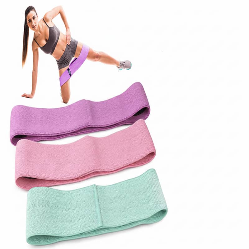 Three resistance bands in purple, pink, and green with a woman exercising in the background.