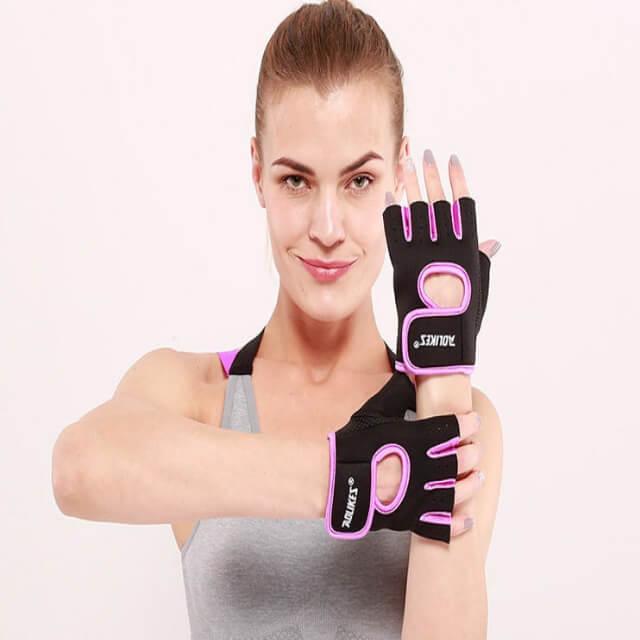Woman wearing black and pink gloves with visible branding on a plain background