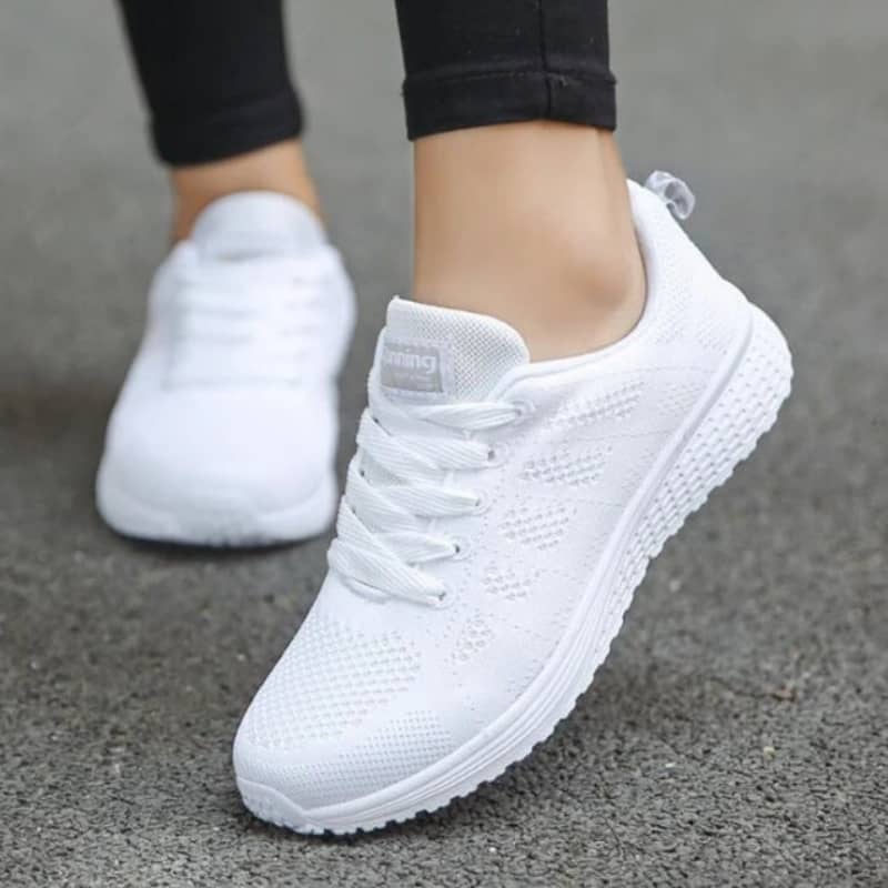White sneakers worn on a gray pavement