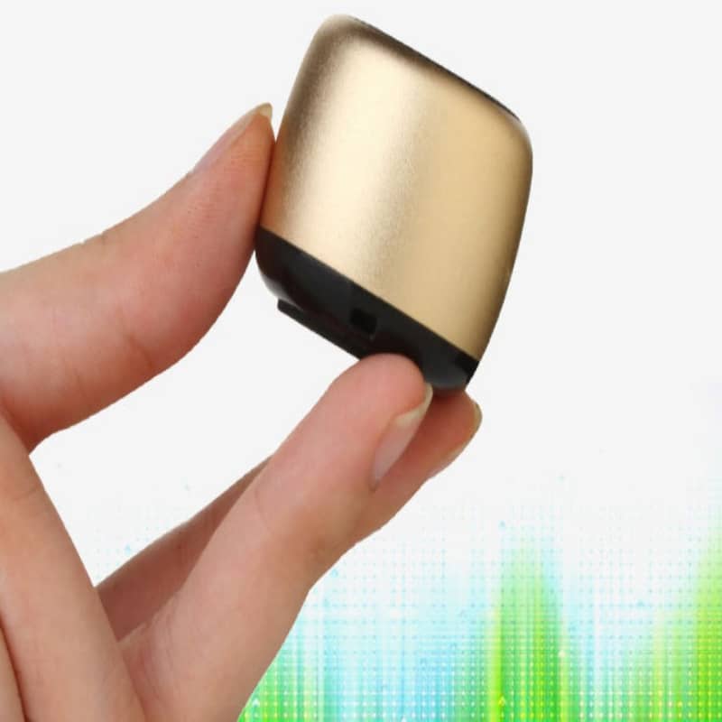 Gold and black electronic device held between fingers with a colorful blurred background