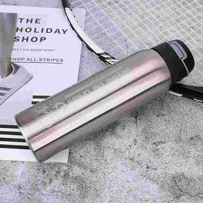 Stainless steel sports water bottle with black lid beside badminton racket on concrete surface