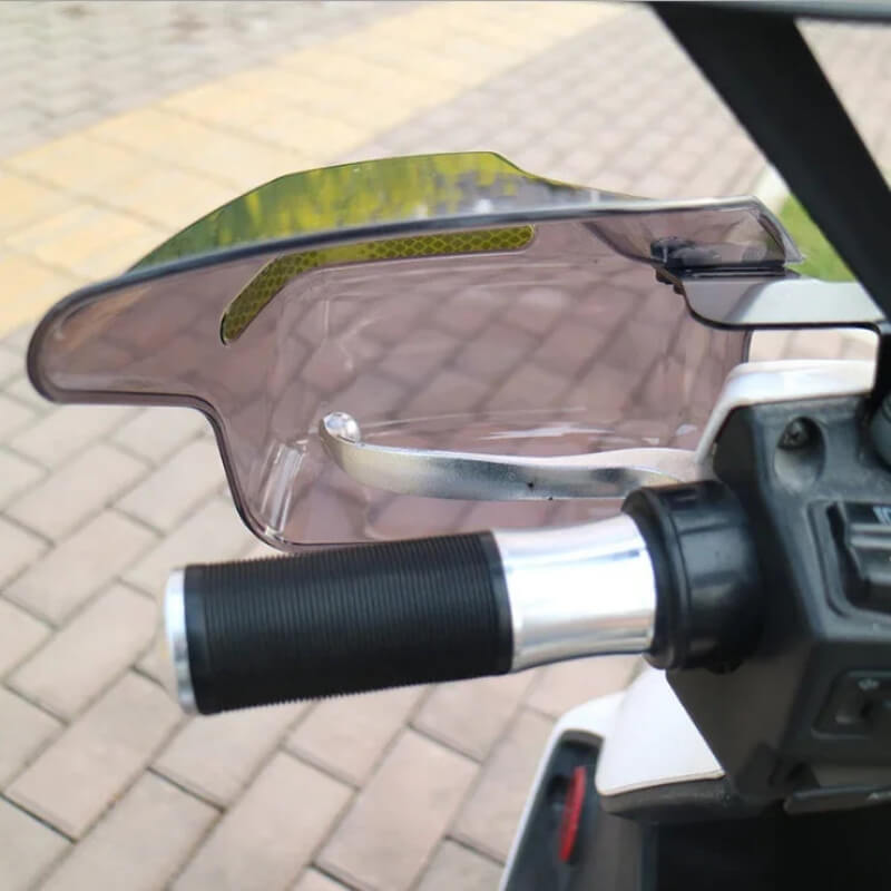 Close-up of motorcycle handlebar with attached wind hand guard on outdoor pavement