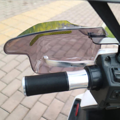 Close-up of motorcycle handlebar with attached wind hand guard on outdoor pavement