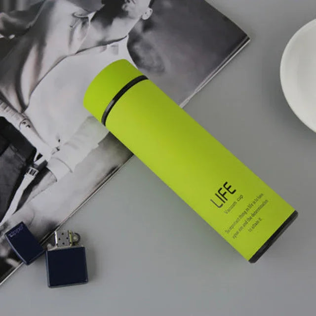 Bright green LIFE branded water bottle for fitness hydration on gray surface with magazine and blue lighter