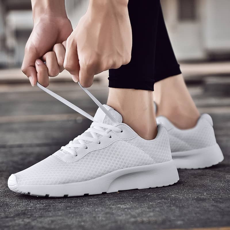 Person tying white sneakers on a blurred background