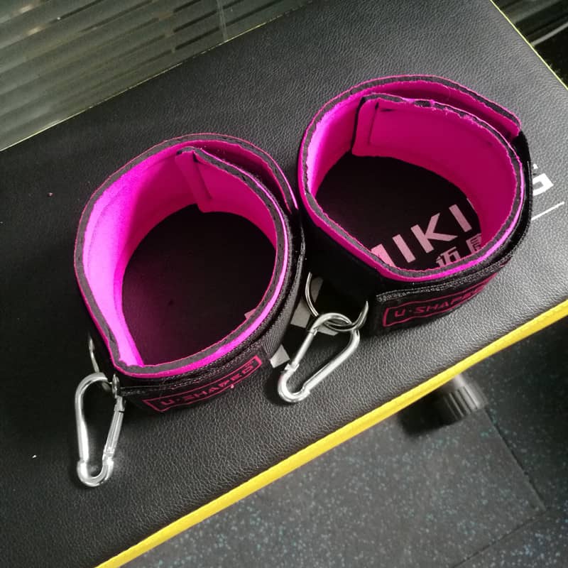 Pink and black straps with carabiners on a dark surface