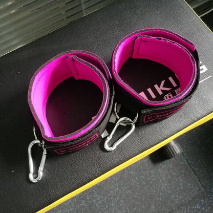 Pink and black straps with carabiners on a dark surface