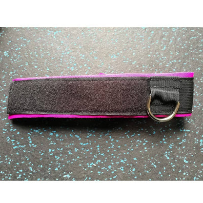 Black and pink strap with a metal ring on a speckled gray surface