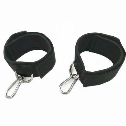 Two black wrist cuffs with metal hooks on a white background