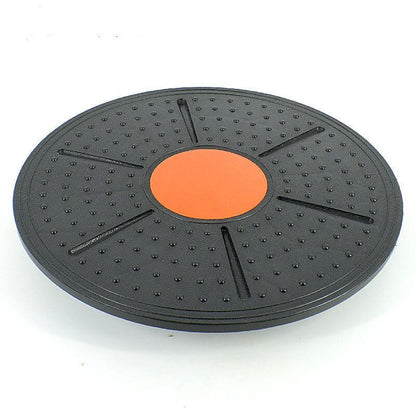 Black exercise disc with an orange center on a white background