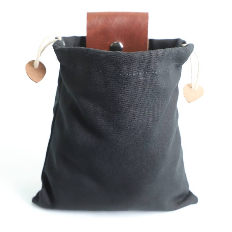 Black drawstring bag with a brown leather tag on a white background