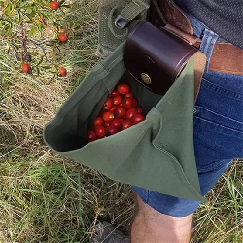Green bag filled with red berries held by a person in a grassy field
