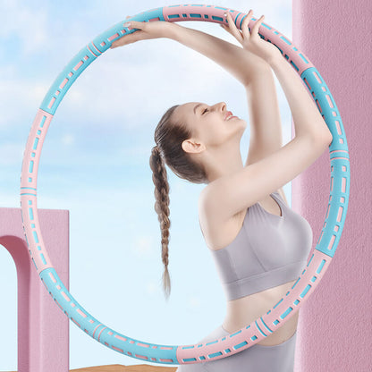 Woman exercising with a pink and blue hula hoop against a light blue sky.