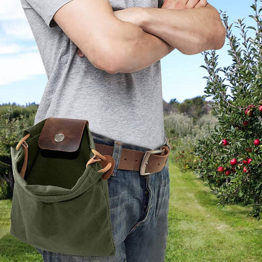 Person wearing a green and brown bag with a belt, standing in an orchard.