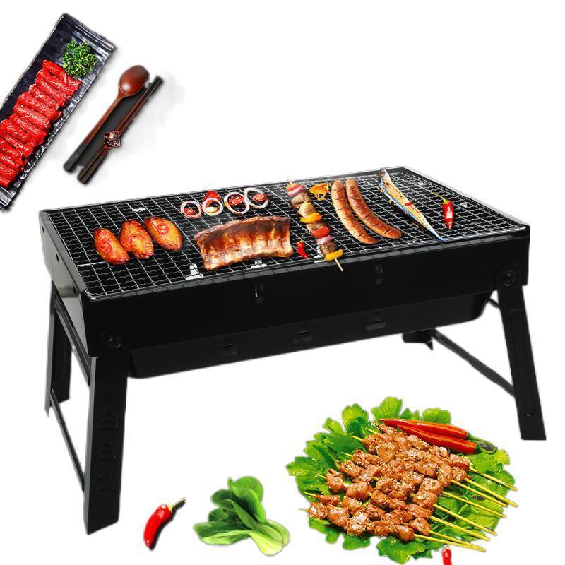 Portable charcoal grill with assorted meat, skewers, and vegetables on a white background