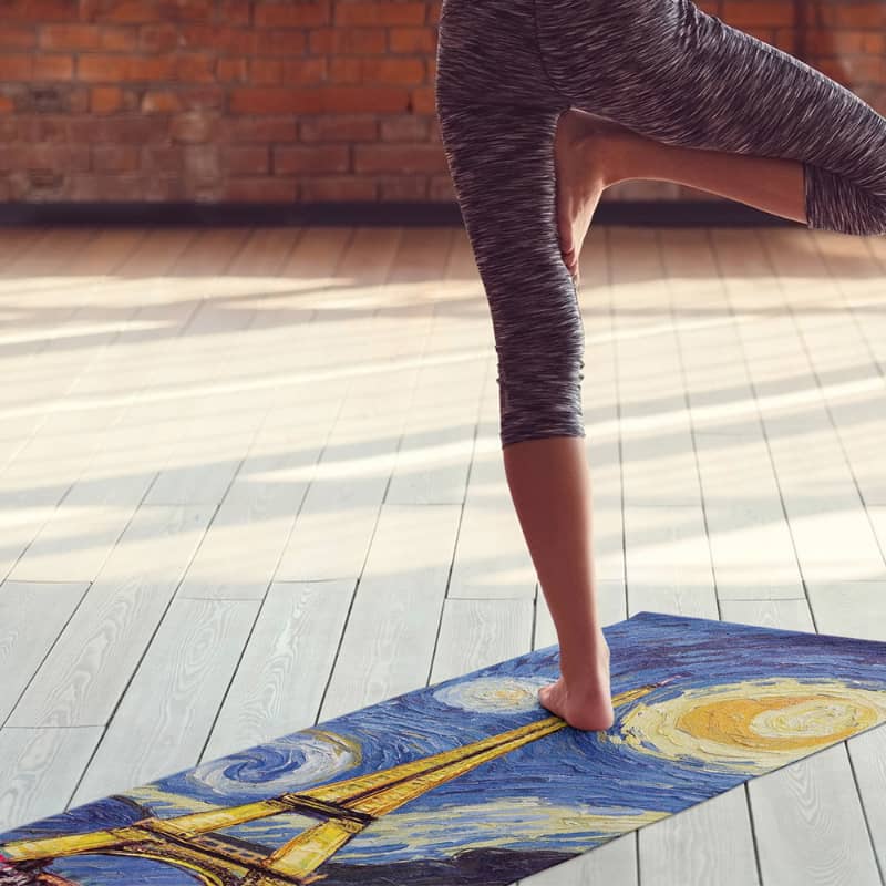 Person practicing yoga on a mat with Van Gogh's 'Starry Night' design.