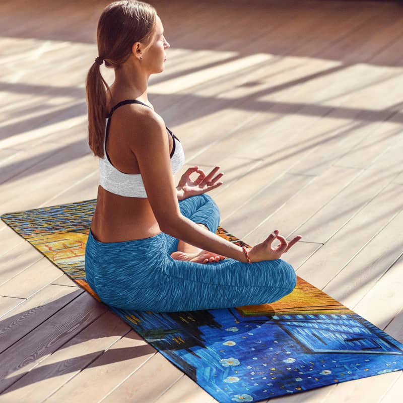 Woman meditating on colorful yoga mat in bright indoor studio, fitness and wellness concept