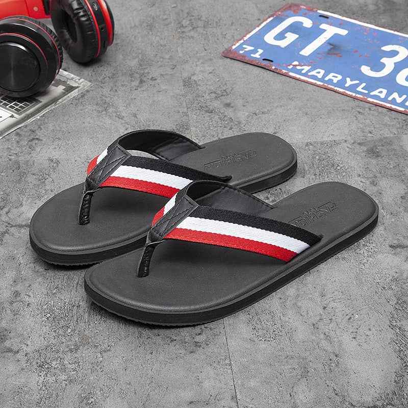 Black flip-flops with red and white stripes on a gray surface.