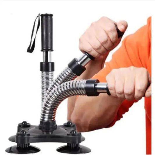 A person's hands and arms are shown using a black and silver wrist/forearm exerciser with suction cup base against a white background.