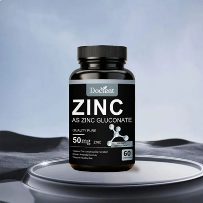 A bottle of DocLet Zinc As Zinc Gluconate dietary supplement, 50mg, 60 capsules, displayed on a reflective silver platform against a soft blue-gray background.