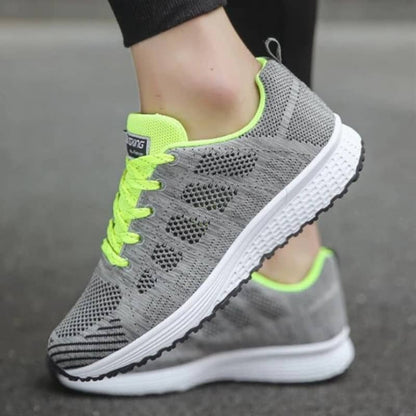 Gray sneakers with neon green accents worn on a blurred background