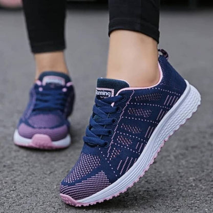 Navy blue athletic shoes with pink accents worn on a gray pavement.