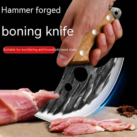 Hammer forged boning knife with wood handle slicing raw meat on a cutting board.
