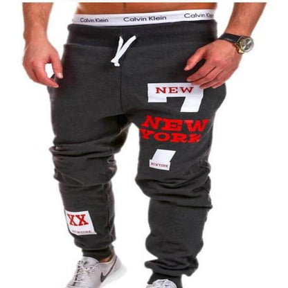 Dark gray sweatpants with 'New York' text and patches on a white background