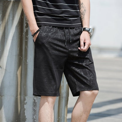 Person wearing black patterned shorts and a striped shirt against a neutral background