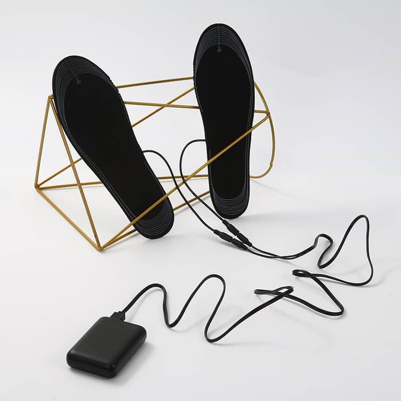 Rechargeable heated insoles with power bank and cables, black, on white background