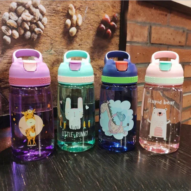 Four colorful kids water bottles with animal designs including giraffe, bunny, dinosaur, and bear on a dark table