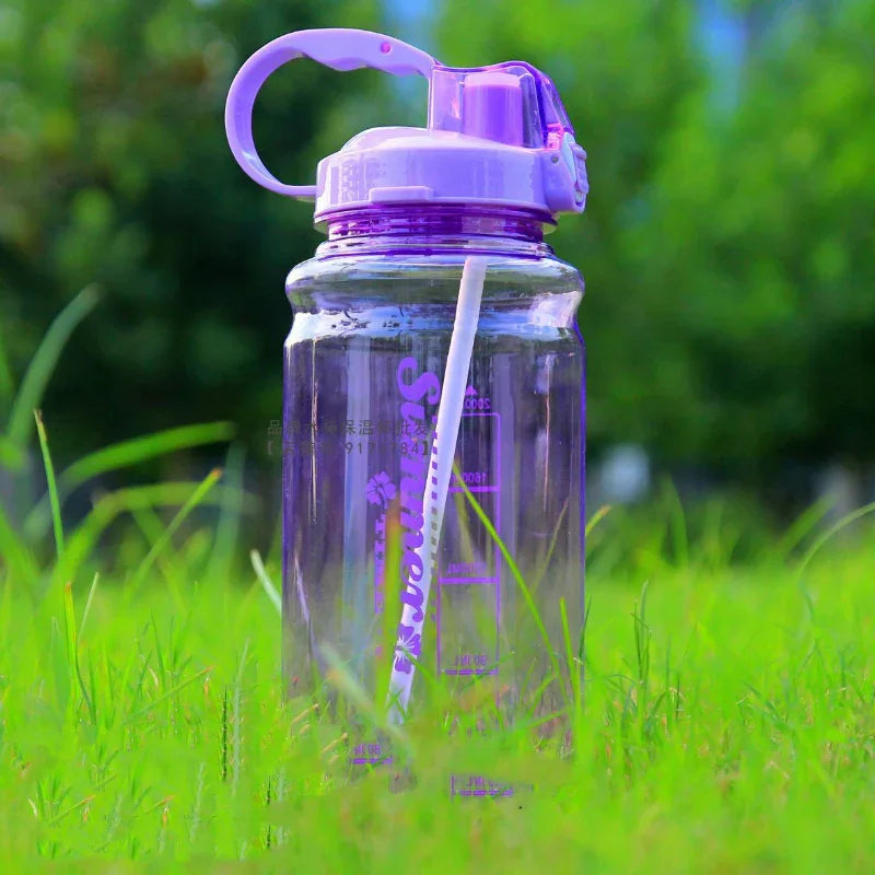 Transparent purple sports water bottle with straw on green grass, outdoor fitness hydration gear