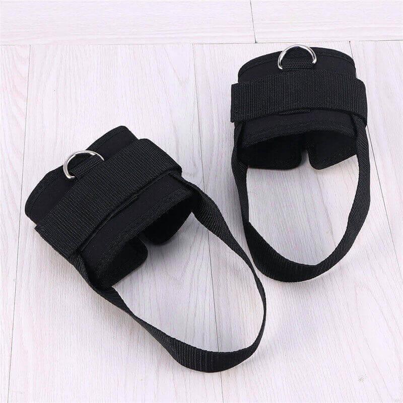 Pair of black ankle straps on a light wooden floor