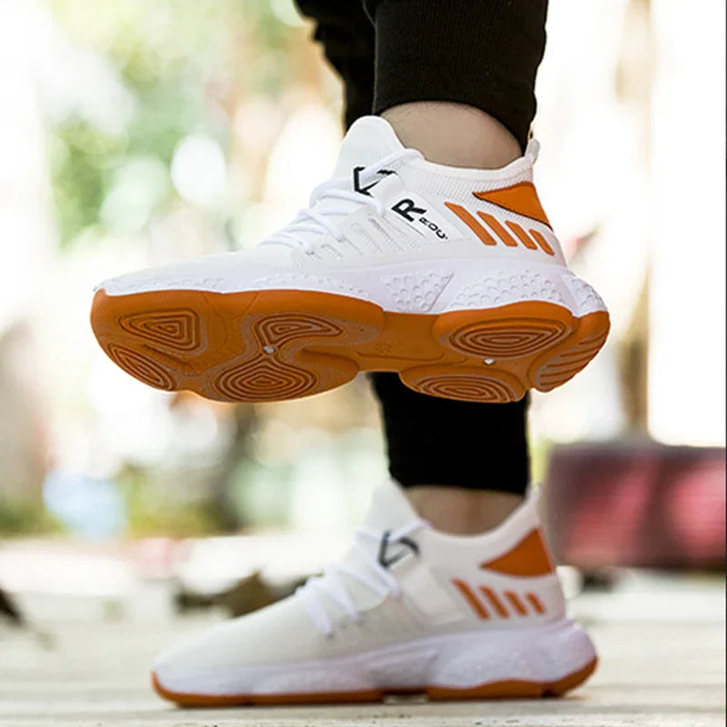 Person wearing white and orange athletic sneakers with textured soles, posing outdoors on wooden floor