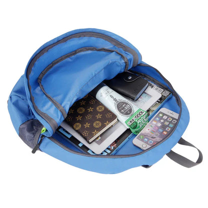 Open blue backpack filled with books, journal, wallet, phone, and travel essentials