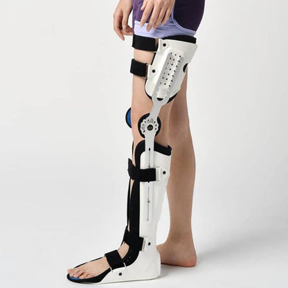 Person wearing a white orthopedic leg brace with black straps on a light gray background