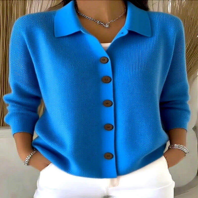 Blue cardigan with brown buttons worn by a person, against a neutral background