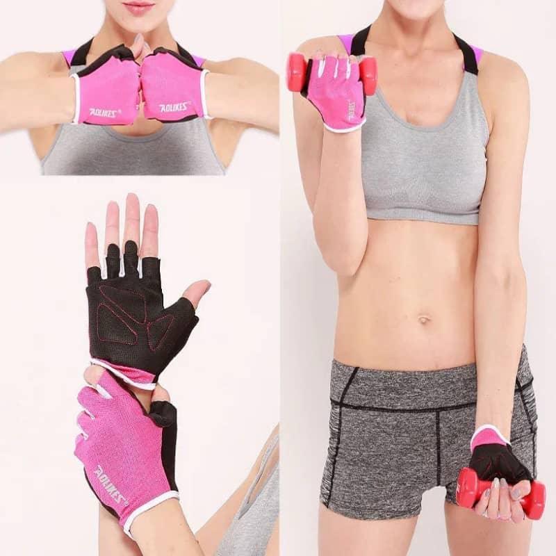 Woman wearing pink fitness gloves holding a dumbbell, shown in gym workout attire.