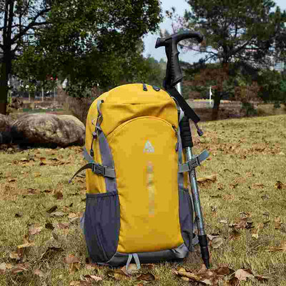 Yellow backpack with a hiking pole on grassy ground with trees in the background