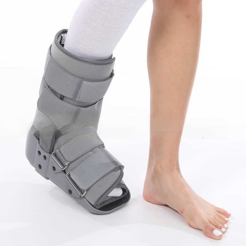 Gray ankle cast brace on a person's leg against a white background